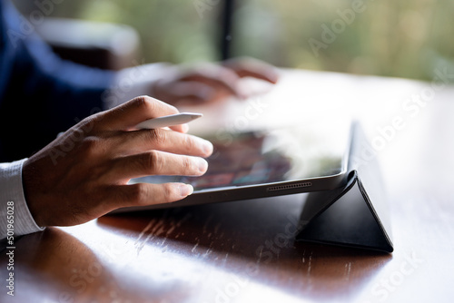 Close up of man's hand using a pen and a laptop.