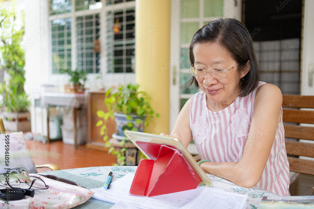Senior Asian Woman Using Digital Tablet to Work From Home Senior Asian Woman Using Digital Tablet to Work From Home