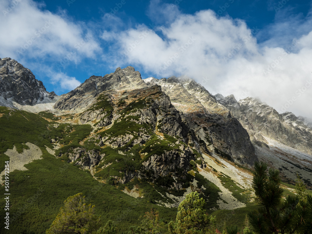 Panoramic view of the autumn mountains. Green and yellow granite mountains against a blue sky with clouds Panoramic view of the autumn mountains. Green and yellow granite mountains against a blue sky with clouds