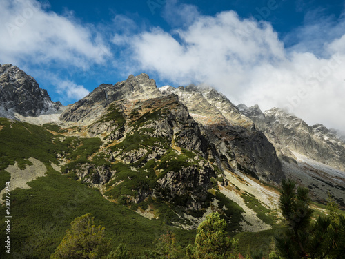Panoramic view of the autumn mountains. Green and yellow granite mountains against a blue sky with clouds