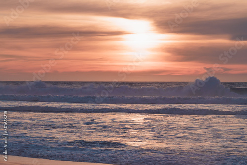 Tropical beach sunset in soft blue and pink colors. Empty sand beach  huge waves  and beautiful cloudy sky