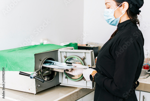 Dentist with a dental sterilizer, A dentist sterilizing his tools, A dentist with a dental autoclave, Close up of a dentist with a steam sterilizer photo