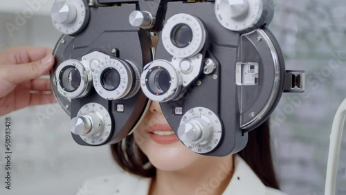 Young female customer being examined visual test using Bifocal Optometry eyesight measurement device by ophthalmologist in optical center, eyecare concept.