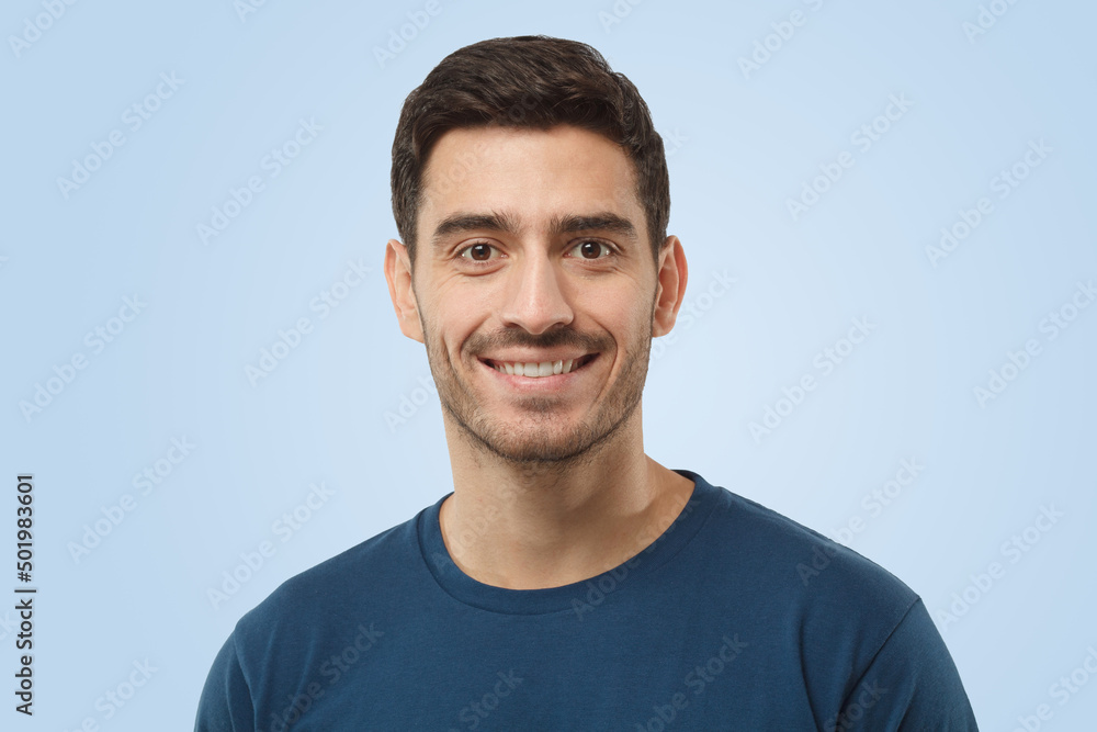 Attractive cheerful handsome man in blue t-shirt on gray background Attractive cheerful handsome man in blue t-shirt on gray background