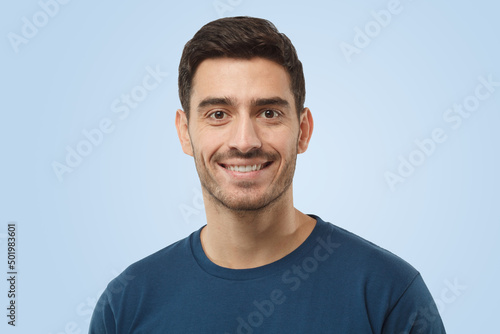 Attractive cheerful handsome man in blue t-shirt on gray background