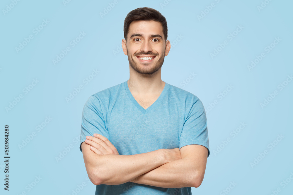 Young happy handsome confident man standing in front of camera with crossed arms Young happy handsome confident man standing in front of camera with crossed arms