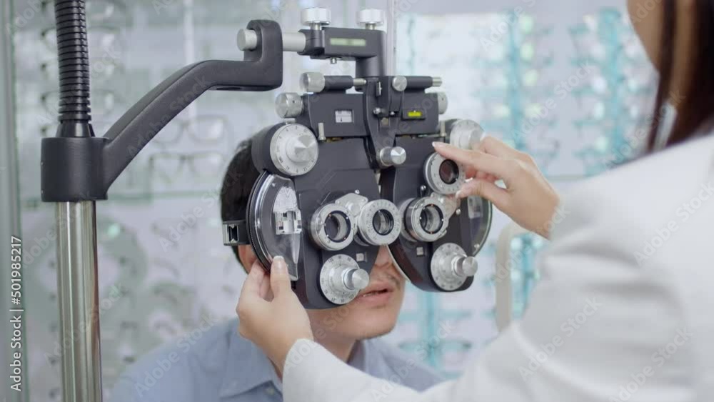 Young male customer being examined visual test using Bifocal Optometry eyesight measurement device by ophthalmologist in optical center, eyecare concept. Young male customer being examined visual test using Bifocal Optometry eyesight measurement device by ophthalmologist in optical center, eyecare concept.