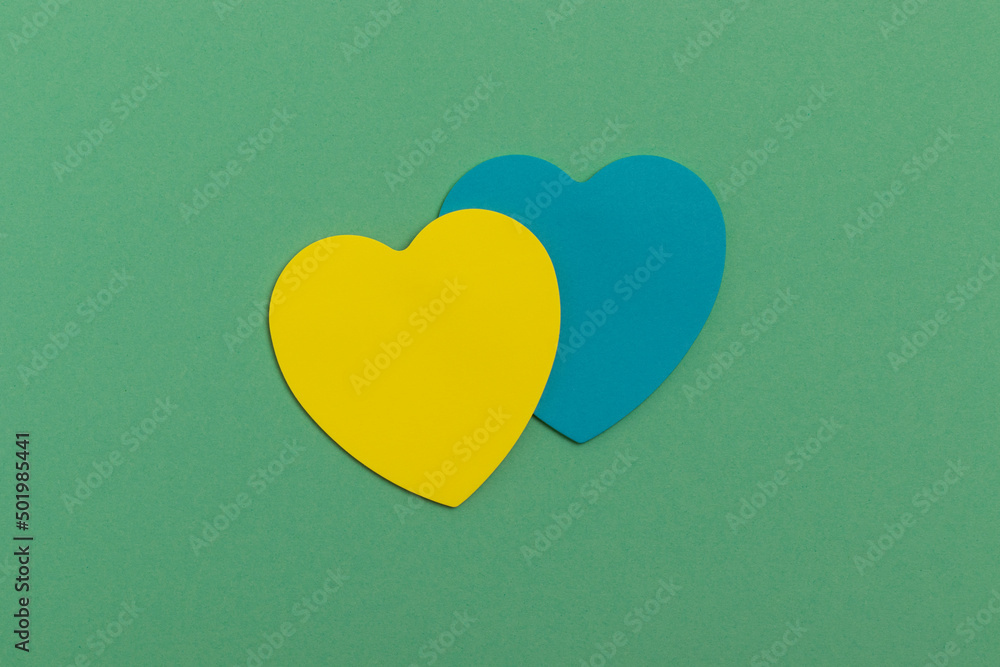 Paper yellow and blue hearts on a turquoise background. Top view.