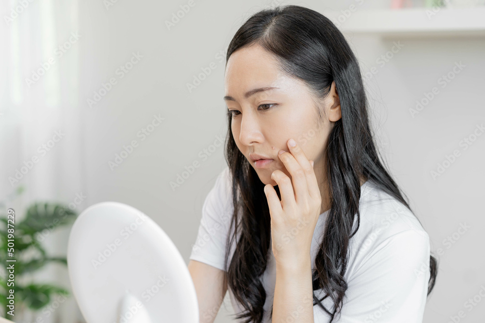 Dermatology, puberty asian young woman, girl looking into mirror, allergic when facial dirty and cosmetic, show squeezing pimple spot on her face. Beauty care from skin problem by acne treatment. Dermatology, puberty asian young woman, girl looking into mirror, allergic when facial dirty and cosmetic, show squeezing pimple spot on her face. Beauty care from skin problem by acne treatment.