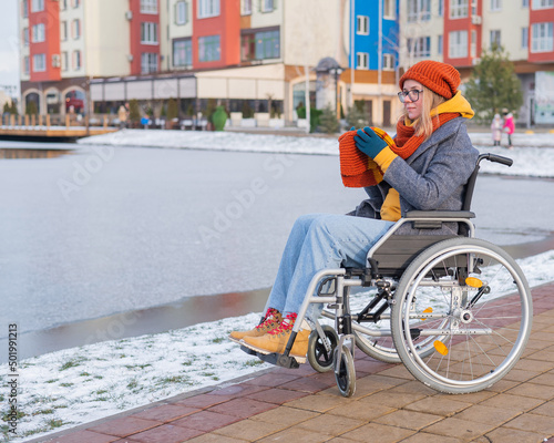 Caucasian woman in a wheelchair walks by the lake in winter.