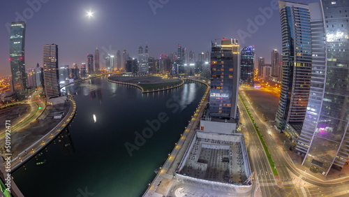 Cityscape panorama of skyscrapers in Dubai Business Bay with water canal aerial night to day timelapse
