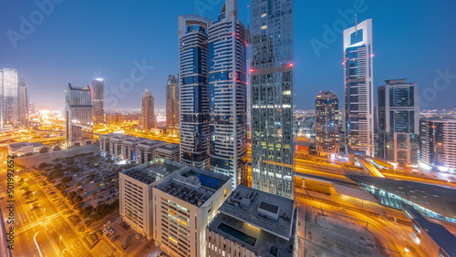 Aerial view of Dubai International Financial District with many skyscrapers night to day timelapse.