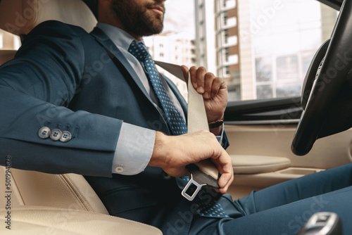 Businessman in formal wear unbuckling after driving car photo