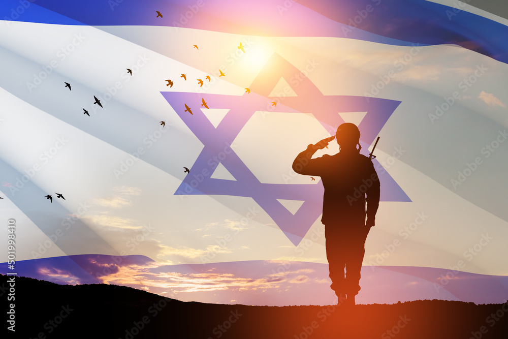 Fototapeta premium Silhouette of soldier saluting against the sunrise in the desert and Israel flag. Concept - armed forces of Israel.