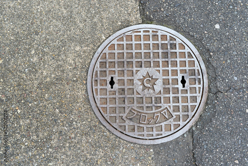 Smiling rusty manhole cover made of iron.