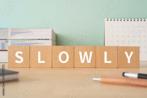 ゆっくりのイメージ｜「SLOWLY」と書かれた積み木が置かれたデスク photo