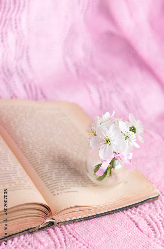 Open old book with white small flowers on a pink background Open old book with white small flowers on a pink background