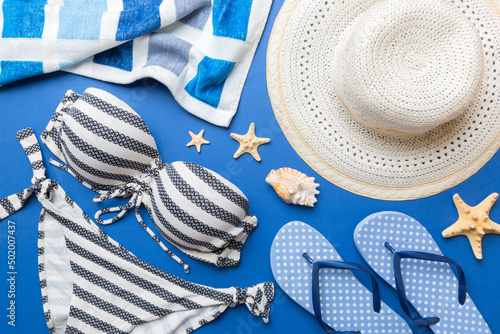 Woman swimwear and beach accessories flat lay top view on colored background Summer travel concept. bikini swimsuit, straw hat and seasheels. Copy space Top view