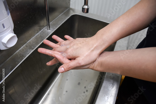 Woman washing hands in a sink with soap.