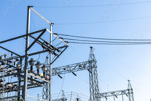 Steel electric poles and lines in High voltage electric power station with sun shine and clear blue sky.