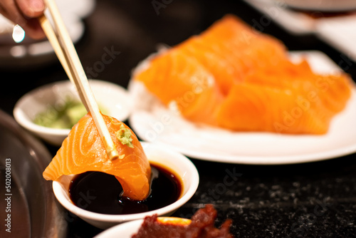 Salmon sashimi slice with shoyu sauce and wasabi. A famous Japanese food style.