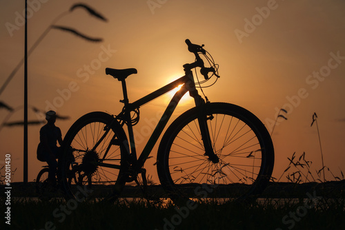 A silhouette of a bike at sunset. The sun shines through the bicycle frame, selective focus