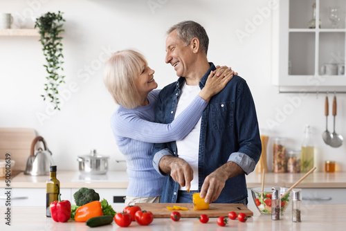 Senior loving couple making healthy salad together in kitchen