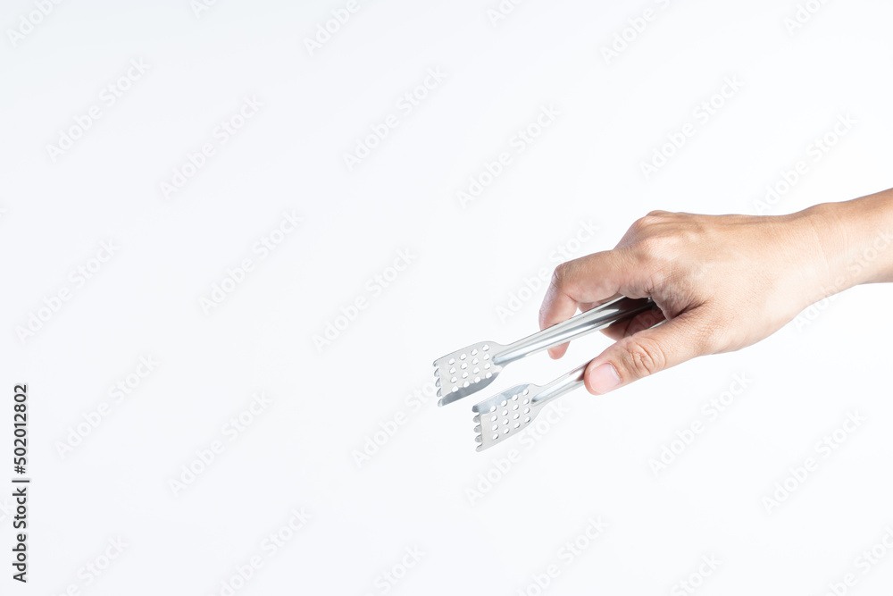 Hand holding silver serving kitchen tongs for picking food Hand holding silver serving kitchen tongs for picking food