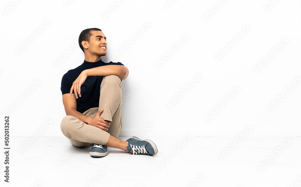 African American man sitting on the floor looking side African American man sitting on the floor looking side