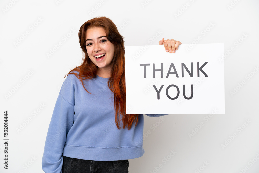 Young redhead woman isolated on white background holding a placard with text THANK YOU with happy expression Young redhead woman isolated on white background holding a placard with text THANK YOU with happy expression