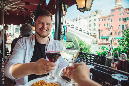 man sitting in cafe eating pasta drinking wine rialto bridge on background venice italy