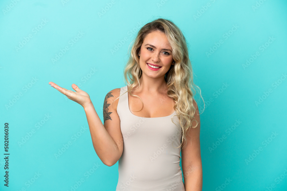 Young Brazilian woman isolated on blue background holding copyspace imaginary on the palm to insert an ad Young Brazilian woman isolated on blue background holding copyspace imaginary on the palm to insert an ad