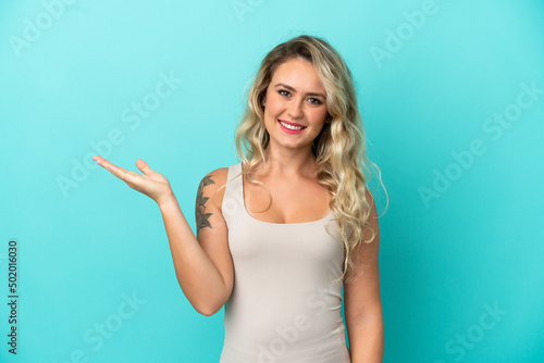 Young Brazilian woman isolated on blue background holding copyspace imaginary on the palm to insert an ad