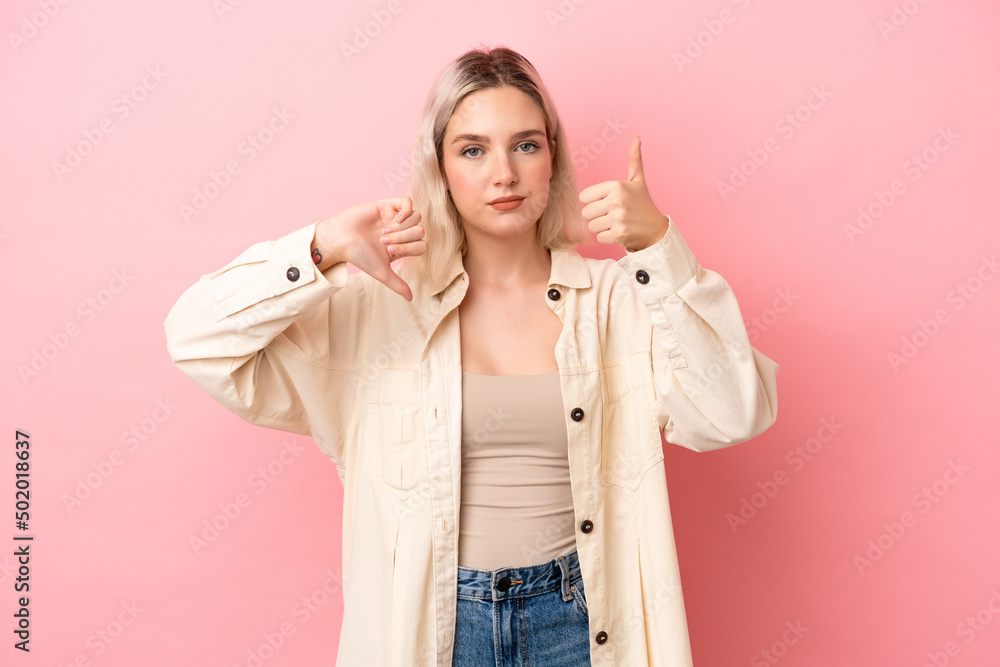 Young caucasian woman isolated on pink background making good-bad sign. Undecided between yes or not Young caucasian woman isolated on pink background making good-bad sign. Undecided between yes or not