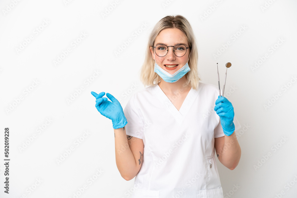 Dentist caucasian woman holding tools isolated on white background pointing finger to the side Dentist caucasian woman holding tools isolated on white background pointing finger to the side