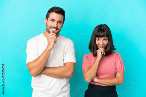 Young couple isolated on blue background smiling and looking to the front with confident face