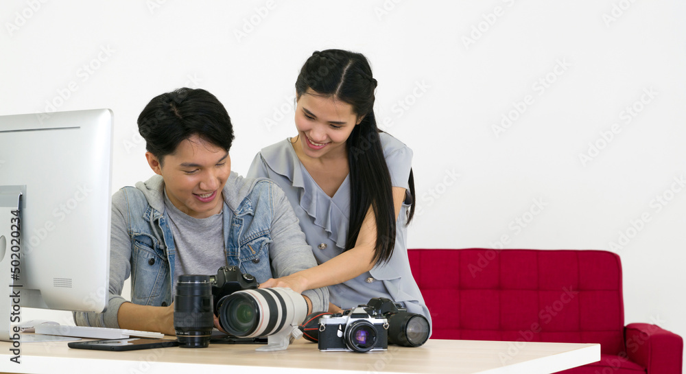 Fototapeta premium Asian photographer and model looking at pictures taken on the camera screen. The young model is very satisfied with her photo. The atmosphere in the photo studio.