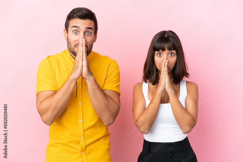 Young couple isolated on pink background keeps palm together. Person asks for something Young couple isolated on pink background keeps palm together. Person asks for something