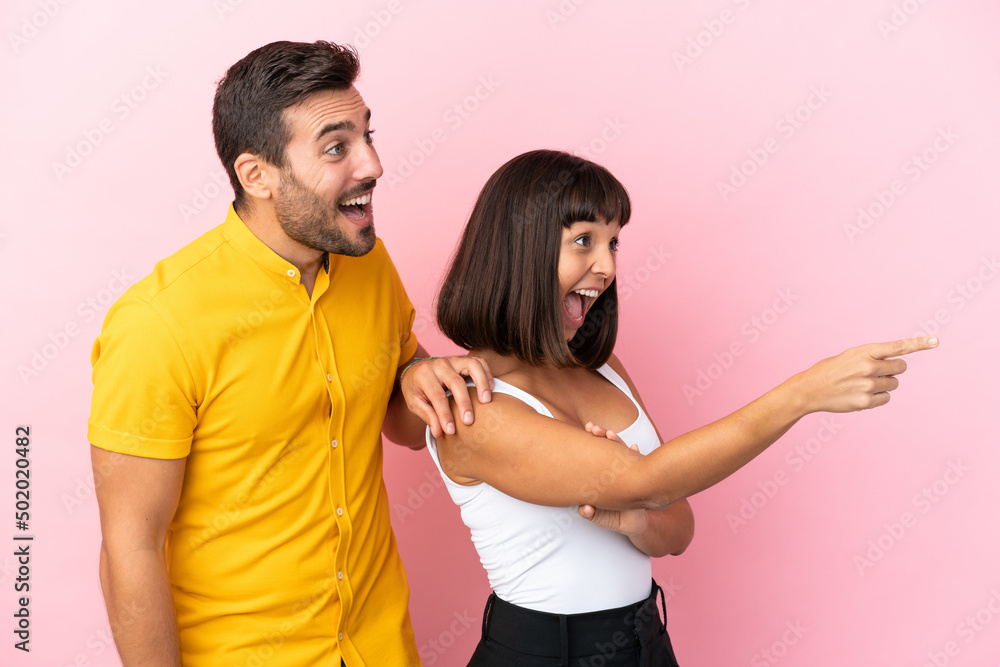 Obraz premium Young couple isolated on pink background presenting an idea while looking smiling towards
