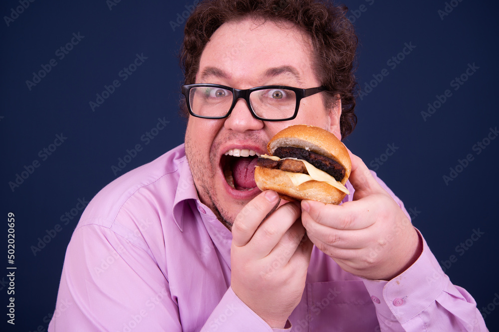 Sport, fitness and healthy lifestyle. Funny fat guy goes in for sports and eats a hamburger. Sport, fitness and healthy lifestyle. Funny fat guy goes in for sports and eats a hamburger.