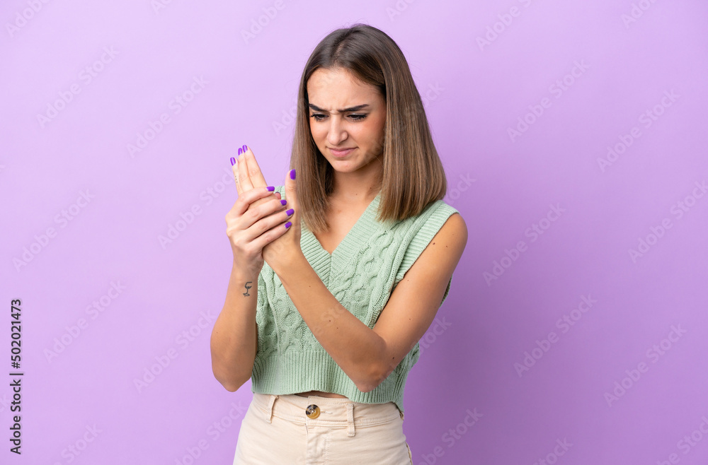 Young caucasian woman isolated on purple background suffering from pain in hands Young caucasian woman isolated on purple background suffering from pain in hands