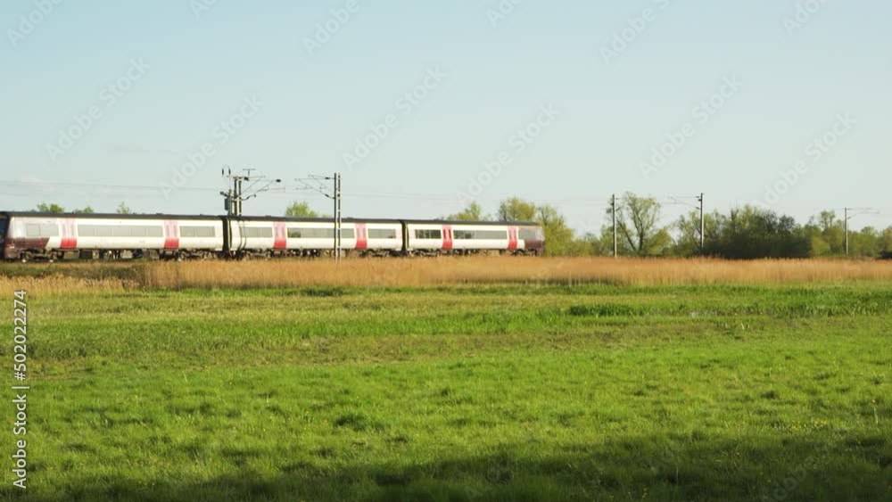 Beautiful summer morning in the countryside, next to the city. A train is arriving at the station going through the fens in a sunny blue sky. Beautiful summer morning in the countryside, next to the city. A train is arriving at the station going through the fens in a sunny blue sky.