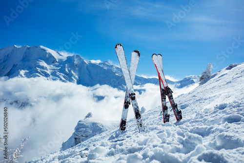 Mountain skis in snow over beautiful snowy alpine peaks