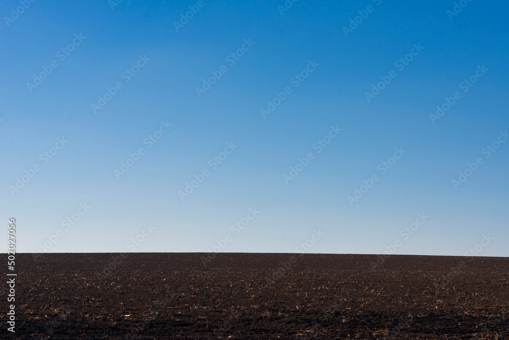Ploughed field and blue sky as background. Ploughed field and blue sky as background.