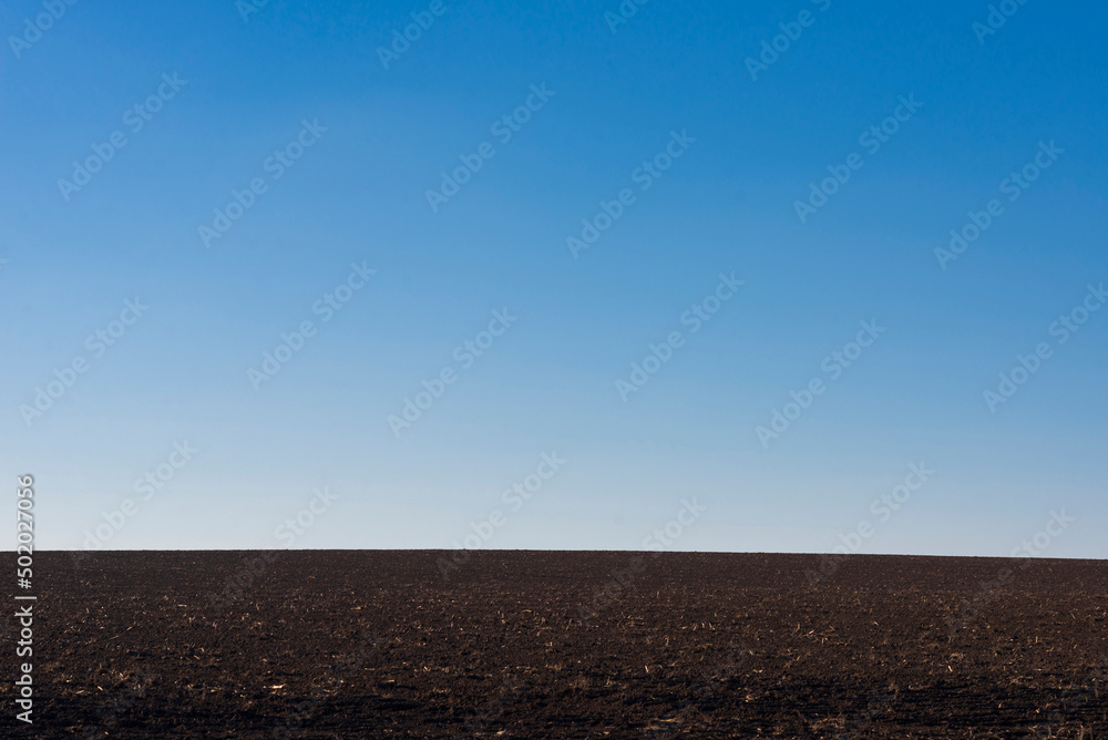 Ploughed field and blue sky as background.