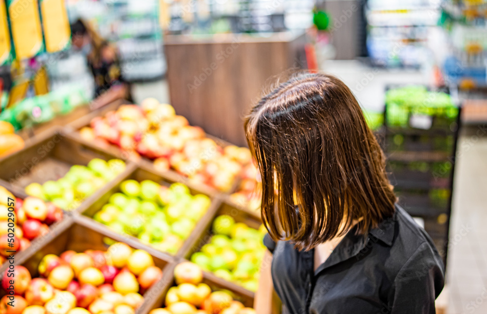 Woman in a supermarket at the shelf for fruits shopping apple