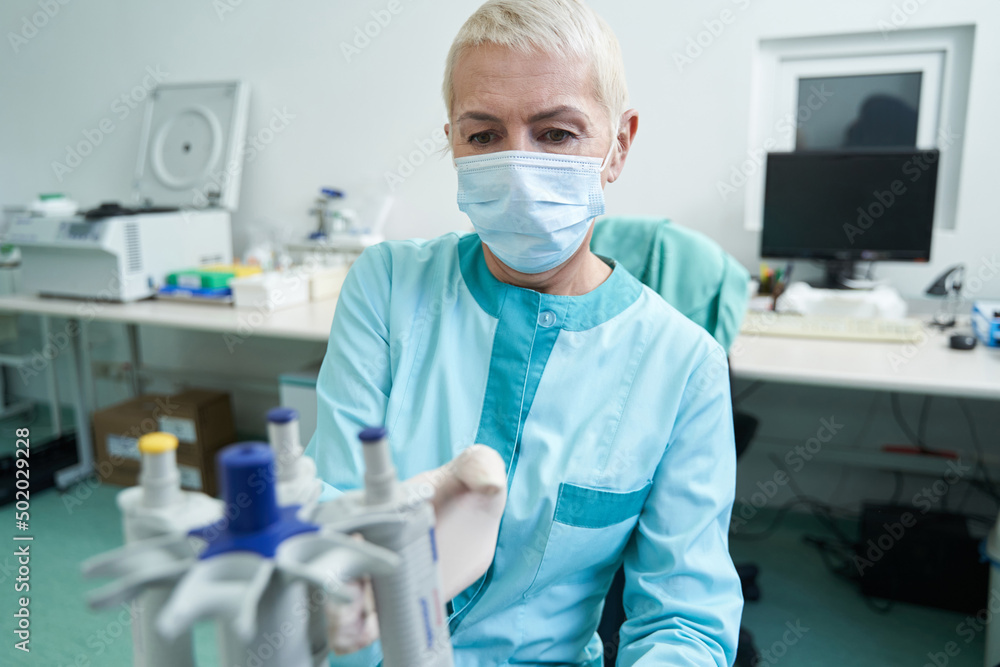 Woman in mask doing blood tests in laboratory Woman in mask doing blood tests in laboratory