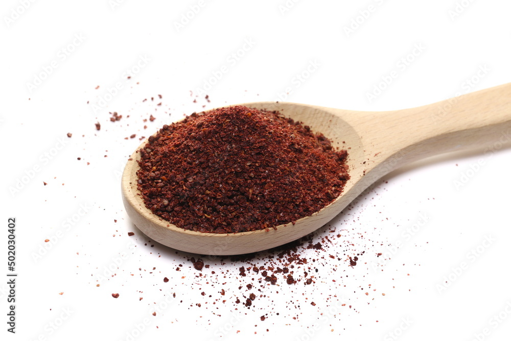 Ground sumac spice, pile in wooden spoon isolated on white 