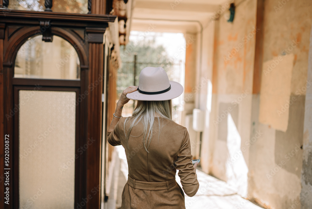 A girl in vintage clothes and a hat walks through the old streets of the city