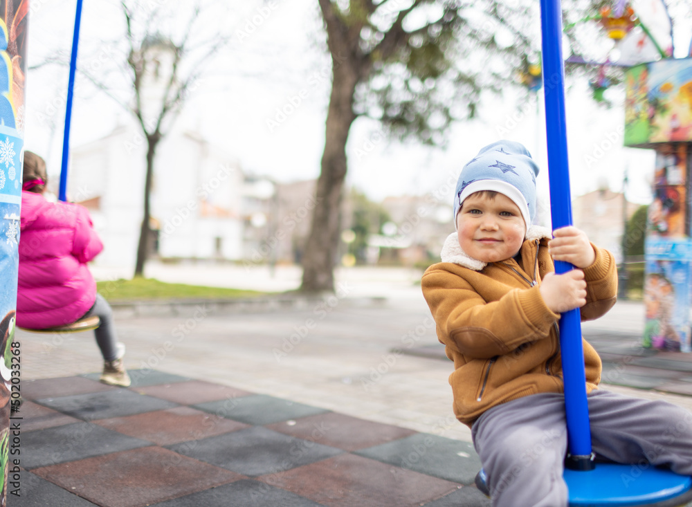 A boy on a playground in an autumn park rides on a swing in cloudy weather A boy on a playground in an autumn park rides on a swing in cloudy weather